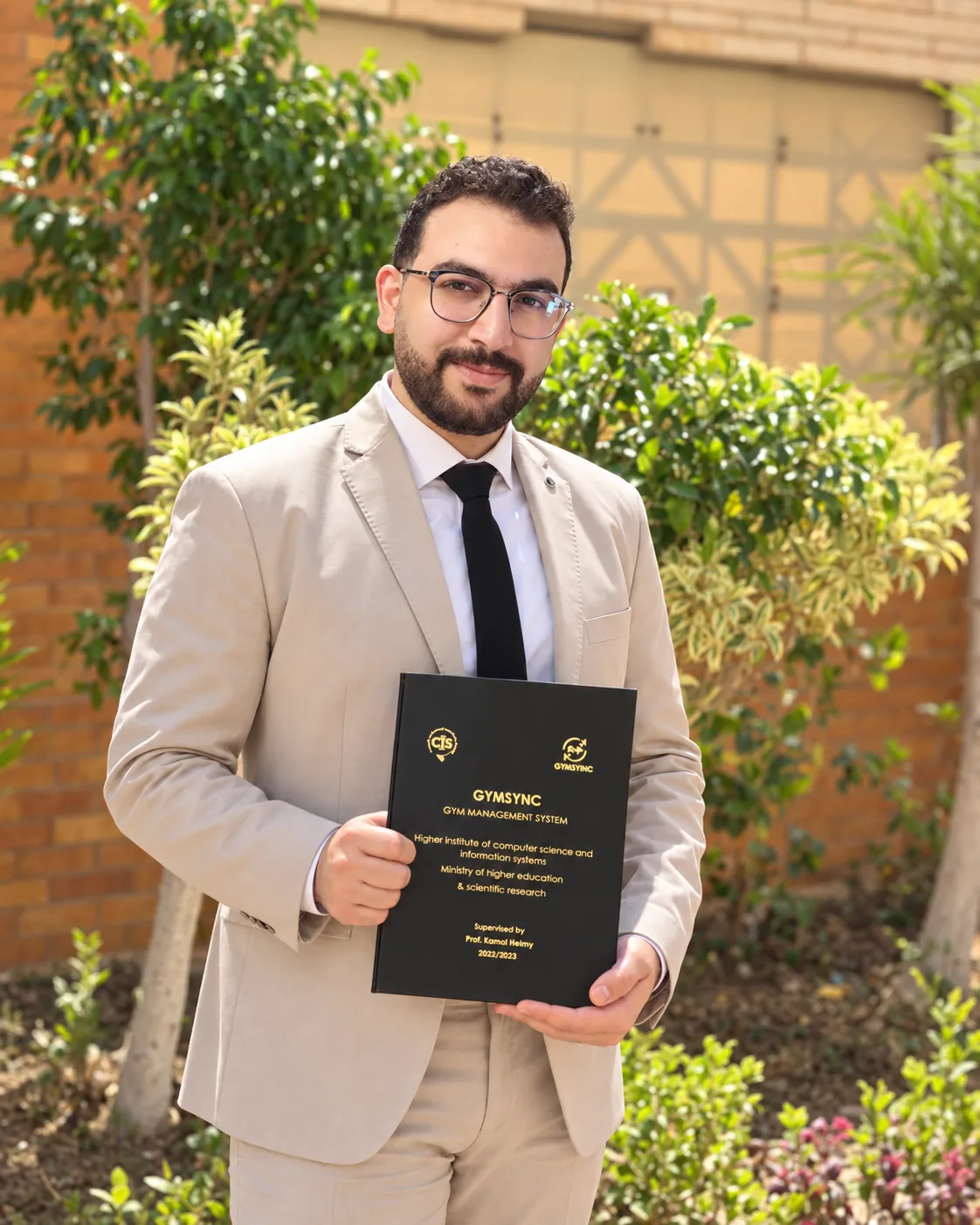 Graduation portrait of Mohamed Ashraf holding his computer science graduation project